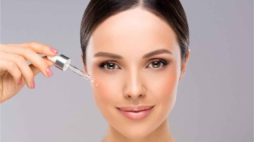 Woman applying hydrating serum to face for glowing skin skincare routine.
