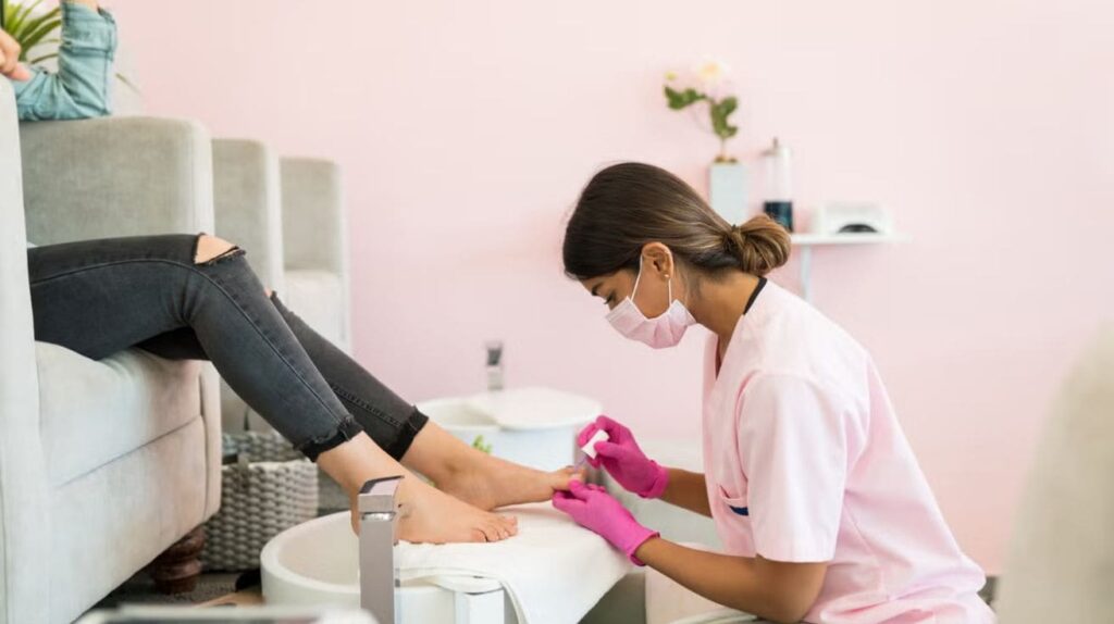 Woman receiving a pedicure in a modern beauty salon while technicians provide foot and nail care.